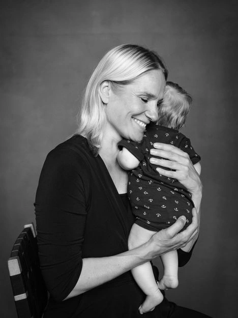 Laura Malmivaara hymyilee ja pitää sylissään pientä poikaansa Aatosta mustavalkoisessa potretissa.