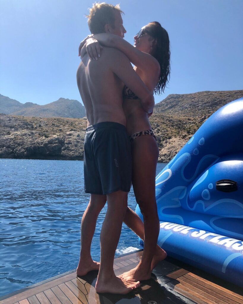 Kimi ja Minttu Räikkönen halaavat toisiaan veneen kannella kesäpäivänä meren rannalla.