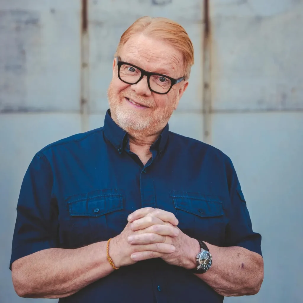 Heikki Silvennoinen hymyilee kameralle sinisessä paidassa.